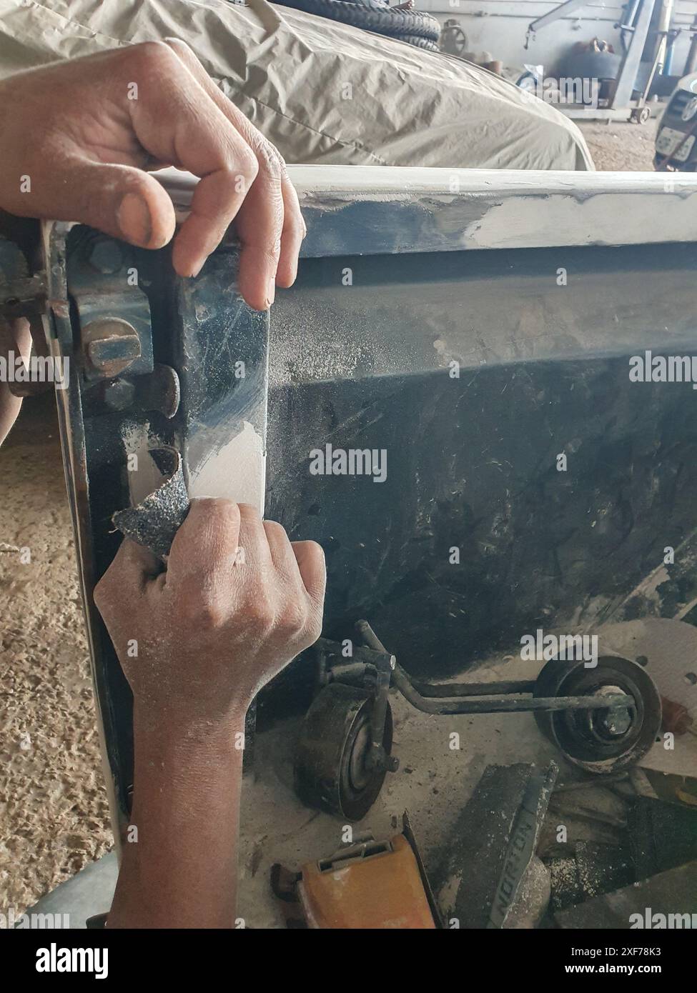Mani di un meccanico che levigano la carrozzeria di una vecchia auto. Foto Stock