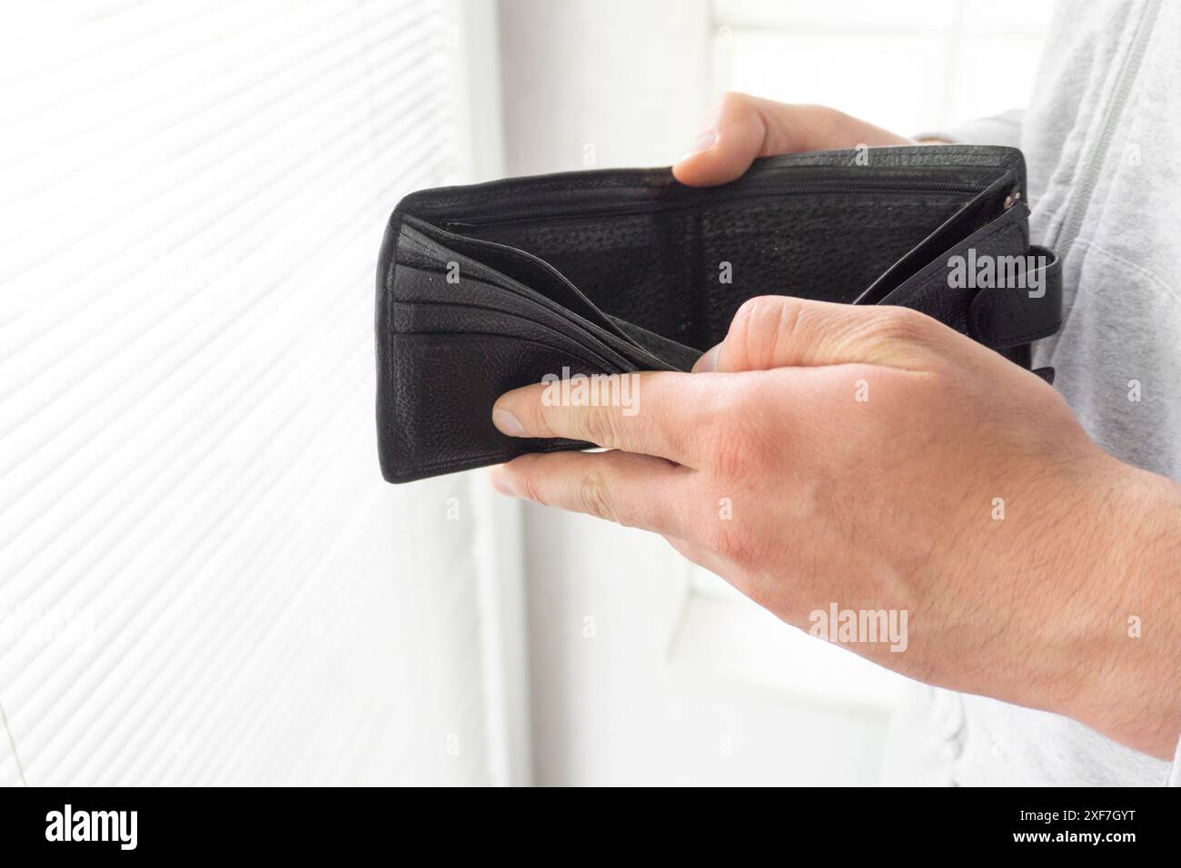 Un uomo che tiene un portafoglio vuoto chiuso, le mani di un pover'uomo aprono una borsa vuota Foto Stock