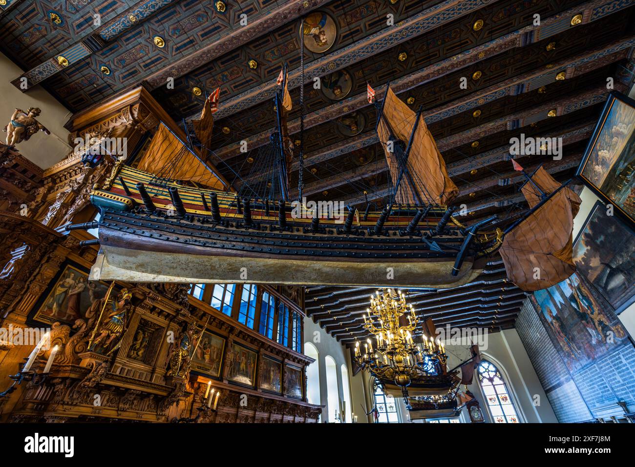 Un modello di nave Orlog pende dal soffitto a cassettoni dipinto del Municipio Superiore di Brema. Quattro di queste navi in miniatura simboleggiano la storia marittima della città anseatica e la sua importanza come città commerciale e portuale. I loro cannoni erano una volta funzionali e venivano sparati in occasioni speciali. Il Municipio Superiore un tempo serviva come sala riunioni del consiglio e ora è utilizzato per occasioni festive. Brema, Germania. Foto Stock