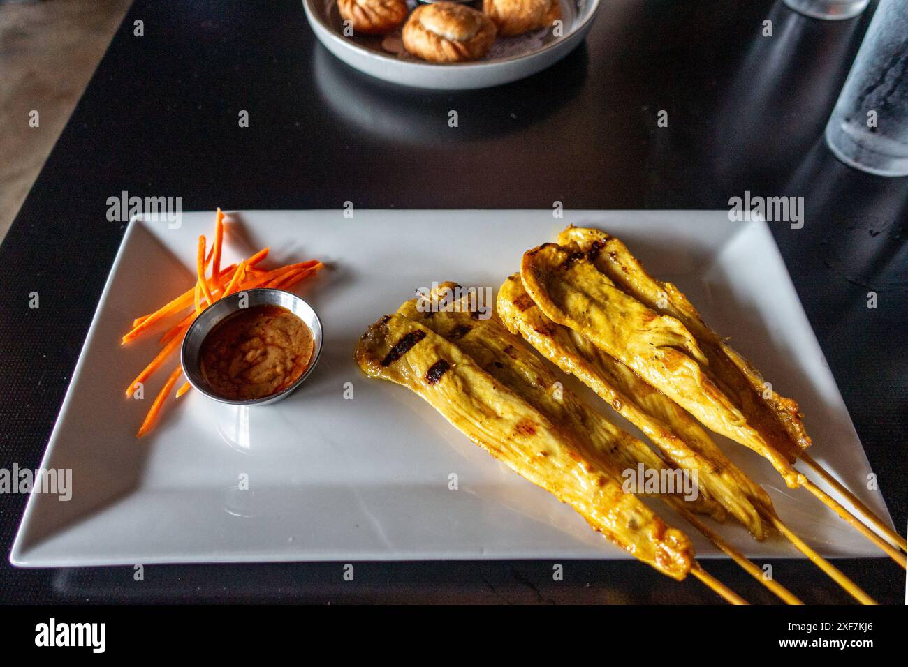 Spiedini di pollo marinati e teneri, grigliati alla perfezione, serviti con cremosa salsa di arachidi. Un'appetitosa miscela di sapori dolci e salati con un tocco Foto Stock