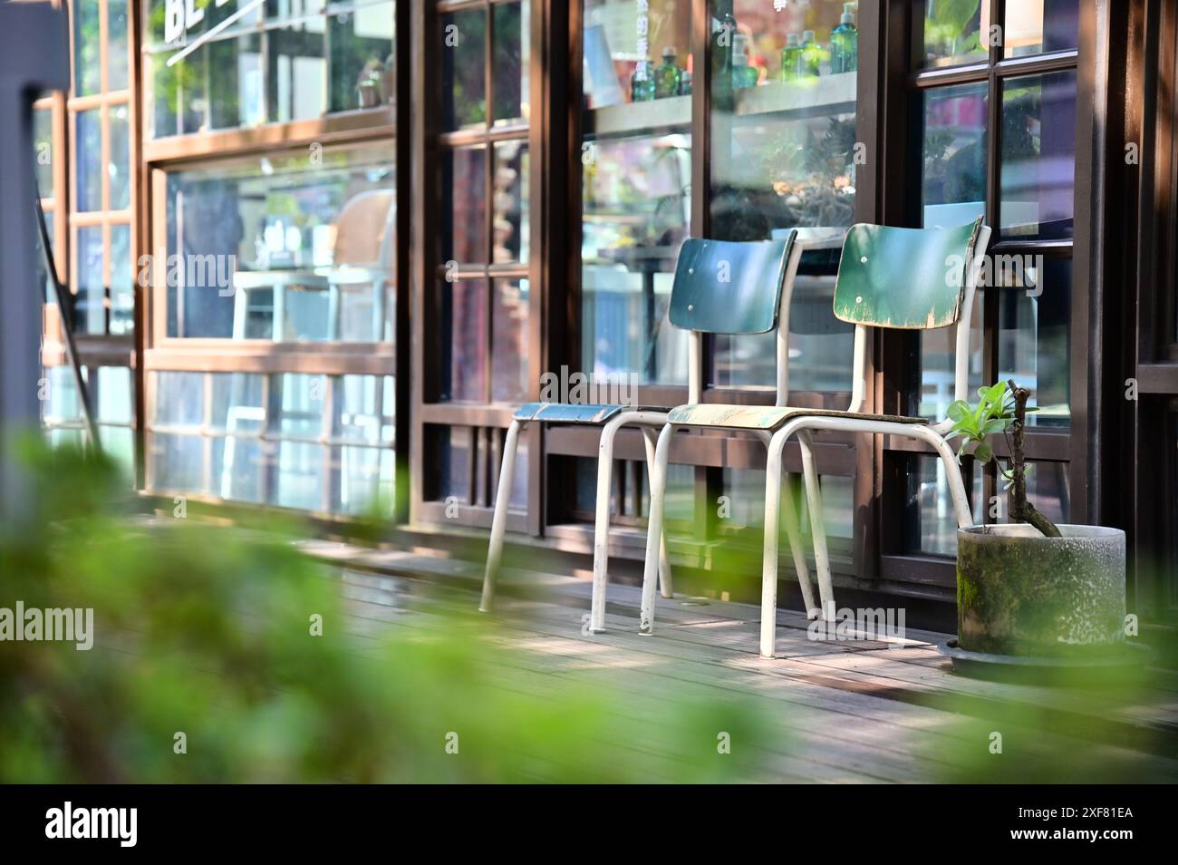 Taiwan - 29 gennaio 2024: Primo piano di due sedie blu della scuola industriale francese su un soleggiato patio mattutino di una casa giapponese in legno. Amato dagli studenti per Foto Stock