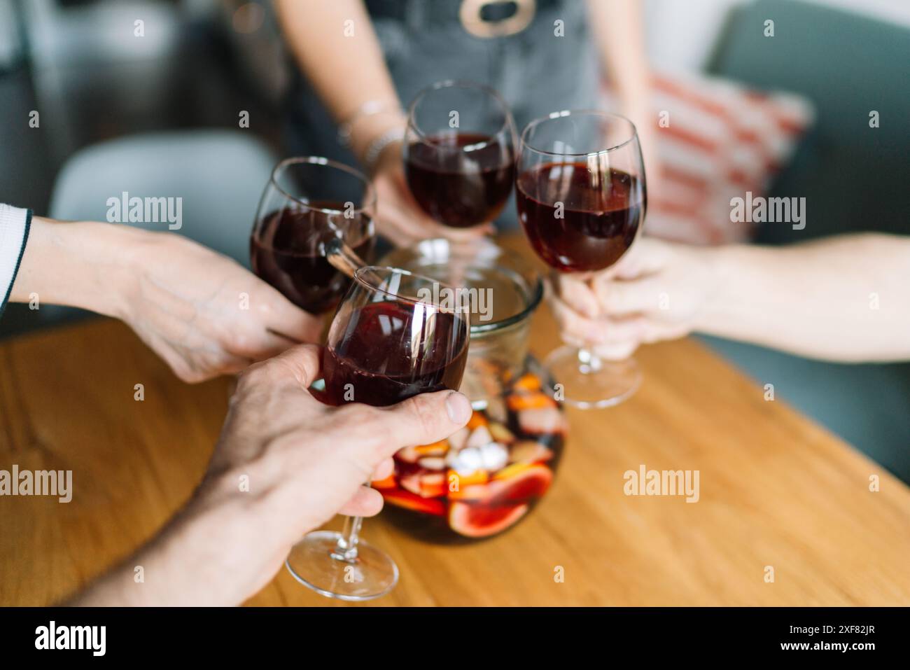 Un gruppo di persone brindano con bicchieri di vino rosso su un tavolo di legno con una caraffa di sangria a Lleida, Spagna. Foto Stock