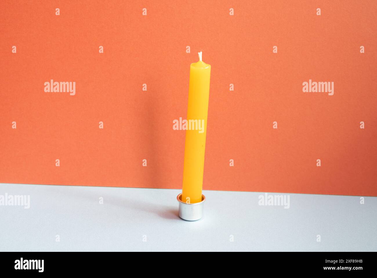 Candela sul tavolo grigio. sfondo rosso della parete Foto Stock