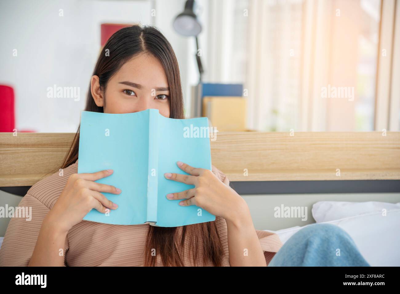 Rilassatevi con una donna che tiene un libro letto alla libreria della biblioteca universitaria. Giovane donna relax leggendo un libro aperto mente per il tempo libero. Bella donna intelligente intelligente Foto Stock