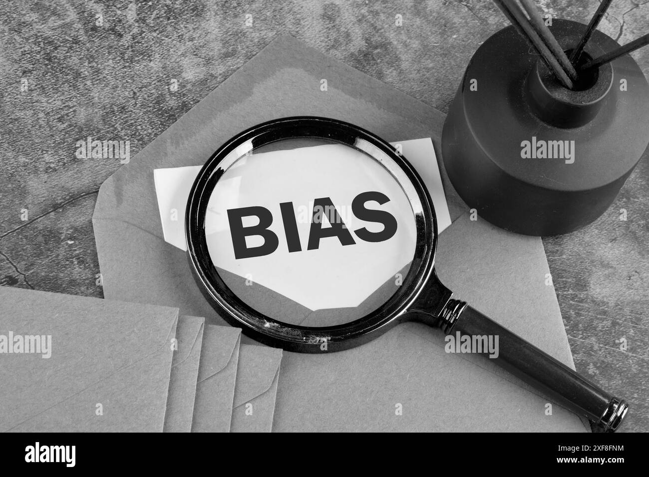 Le opinioni personali il pregiudizio il concetto di pregiudizio è apparso attraverso una lente d'ingrandimento su un pezzo di carta che fuoriesce da una busta. Immagine in bianco e nero Foto Stock