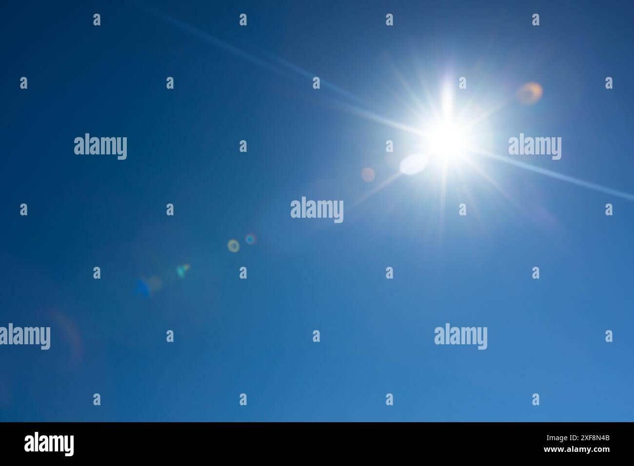 Effetto riflesso dell'obiettivo sul cielo blu intenso con sole incandescente Foto Stock