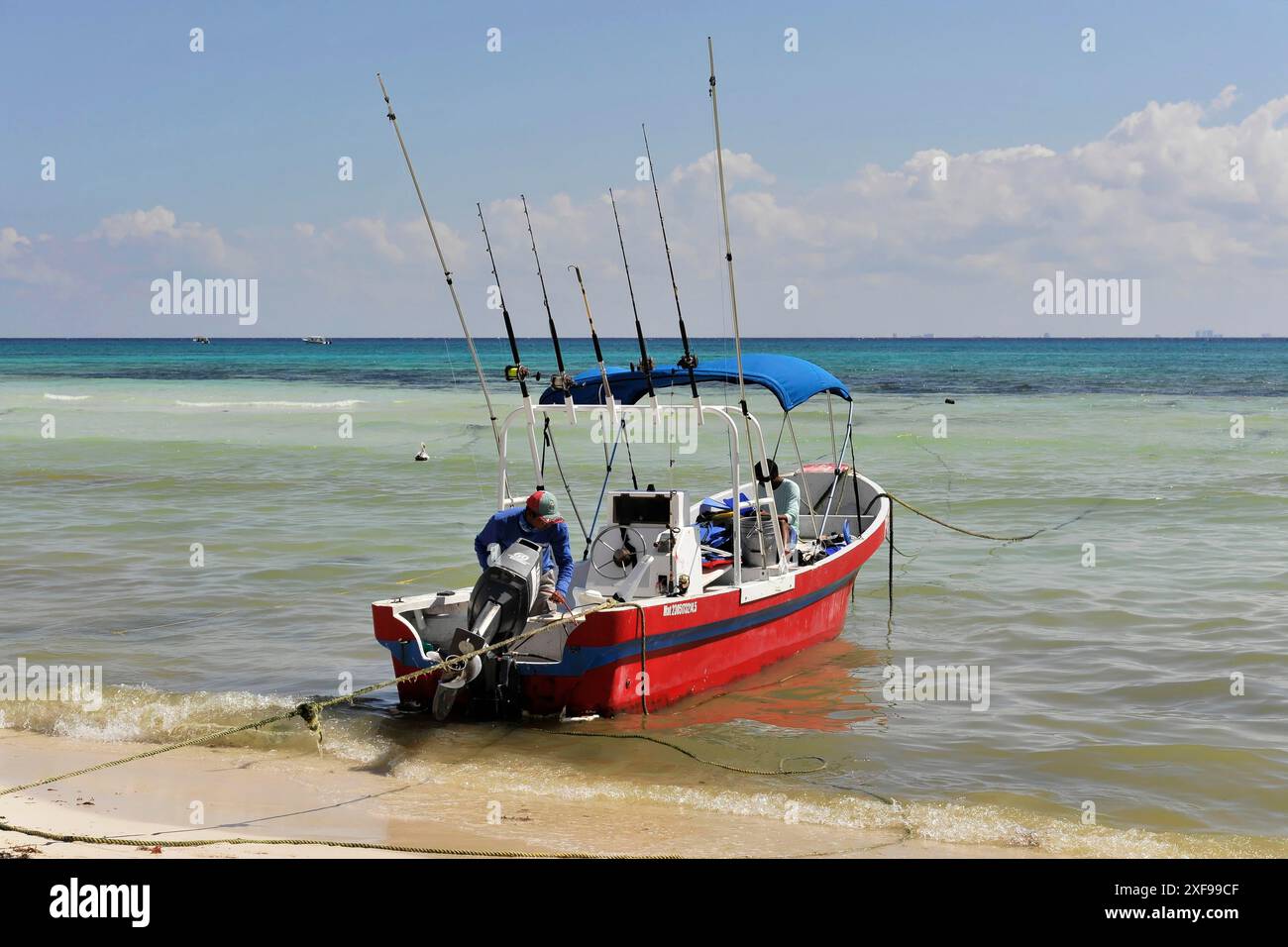 Paamul, Quintana Roo, Messico, America centrale, Una barca con linee di pesca sulla riva di una spiaggia tranquilla con acque cristalline e cielo blu, regione dello Yucatan Foto Stock