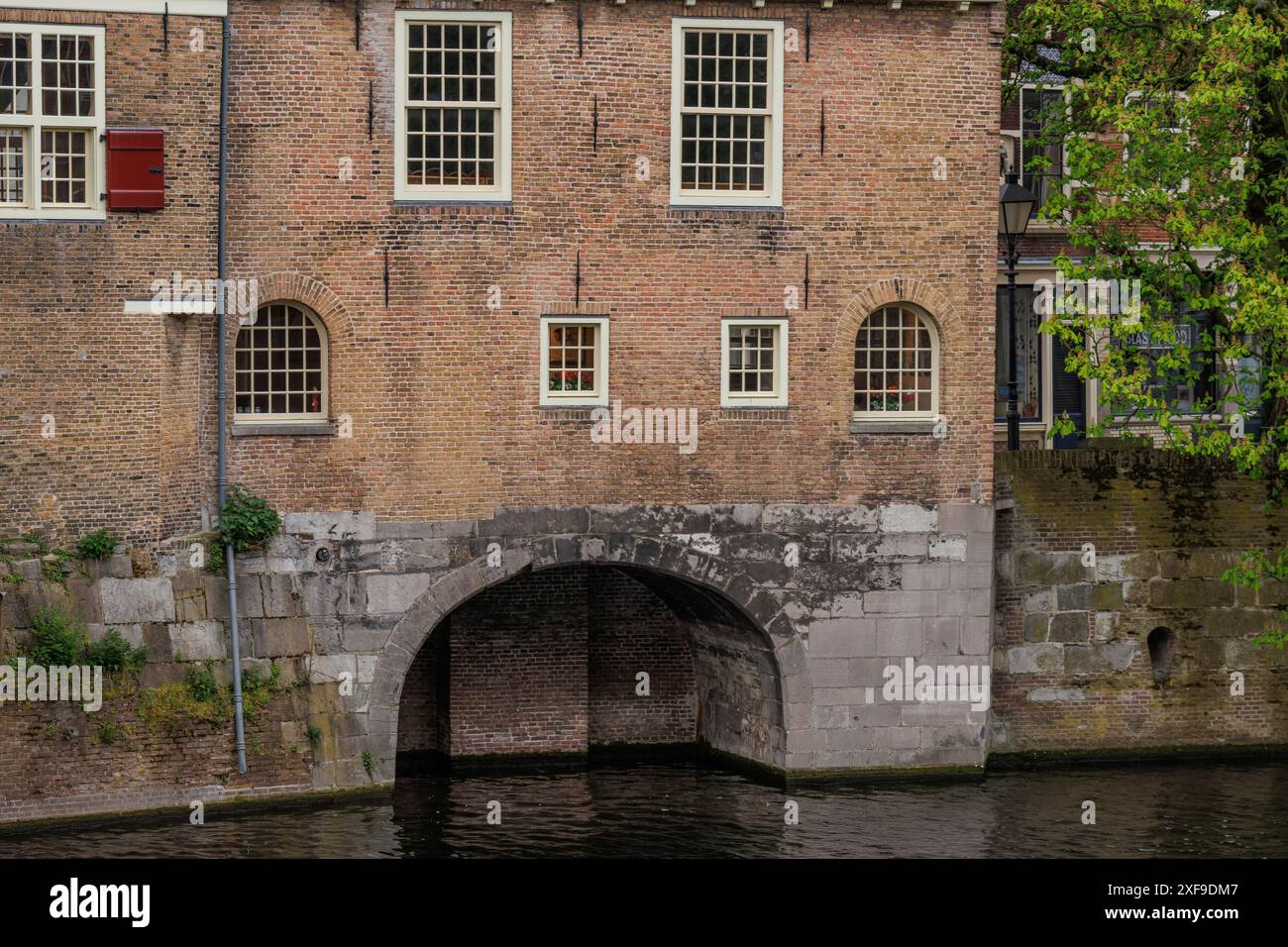 Muro in mattoni con diverse finestre e un grande arco che conduce all'acqua, Rotterdam, Paesi Bassi Foto Stock