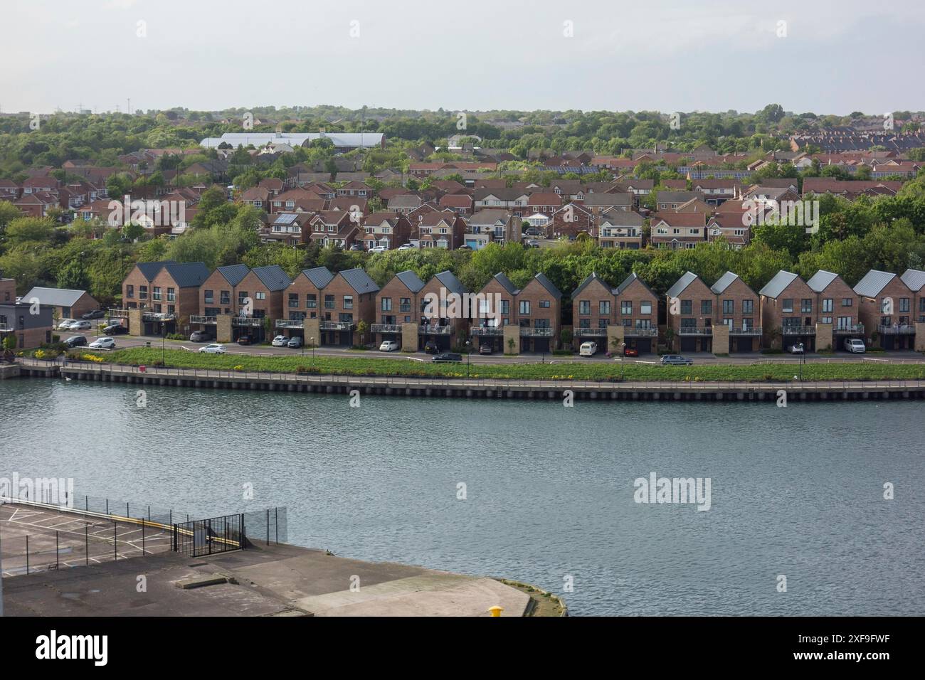 Il fiume scorre accanto a una fila di case moderne con dintorni verdi e atmosfera urbana, newcastle, Inghilterra, Regno Unito Foto Stock