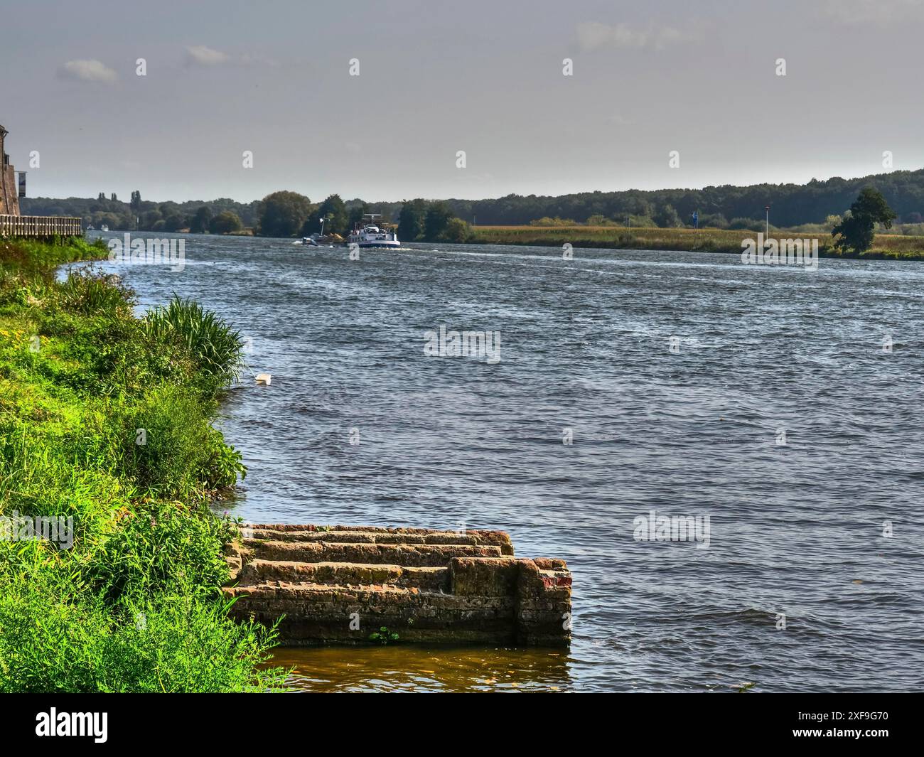 Un fiume calmo con sponde verdi e un cielo ampio e limpido, con un tocco di natura e pace, Kessel, Paesi Bassi Foto Stock