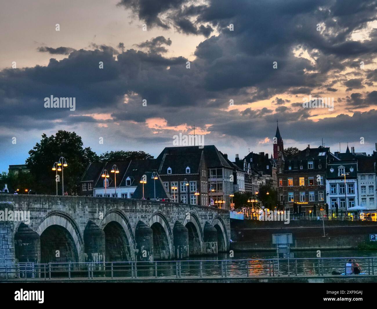 Romantica vista sulla città con fiume e ponte vecchio al crepuscolo, case e cielo illuminato, maastricht, paesi bassi Foto Stock