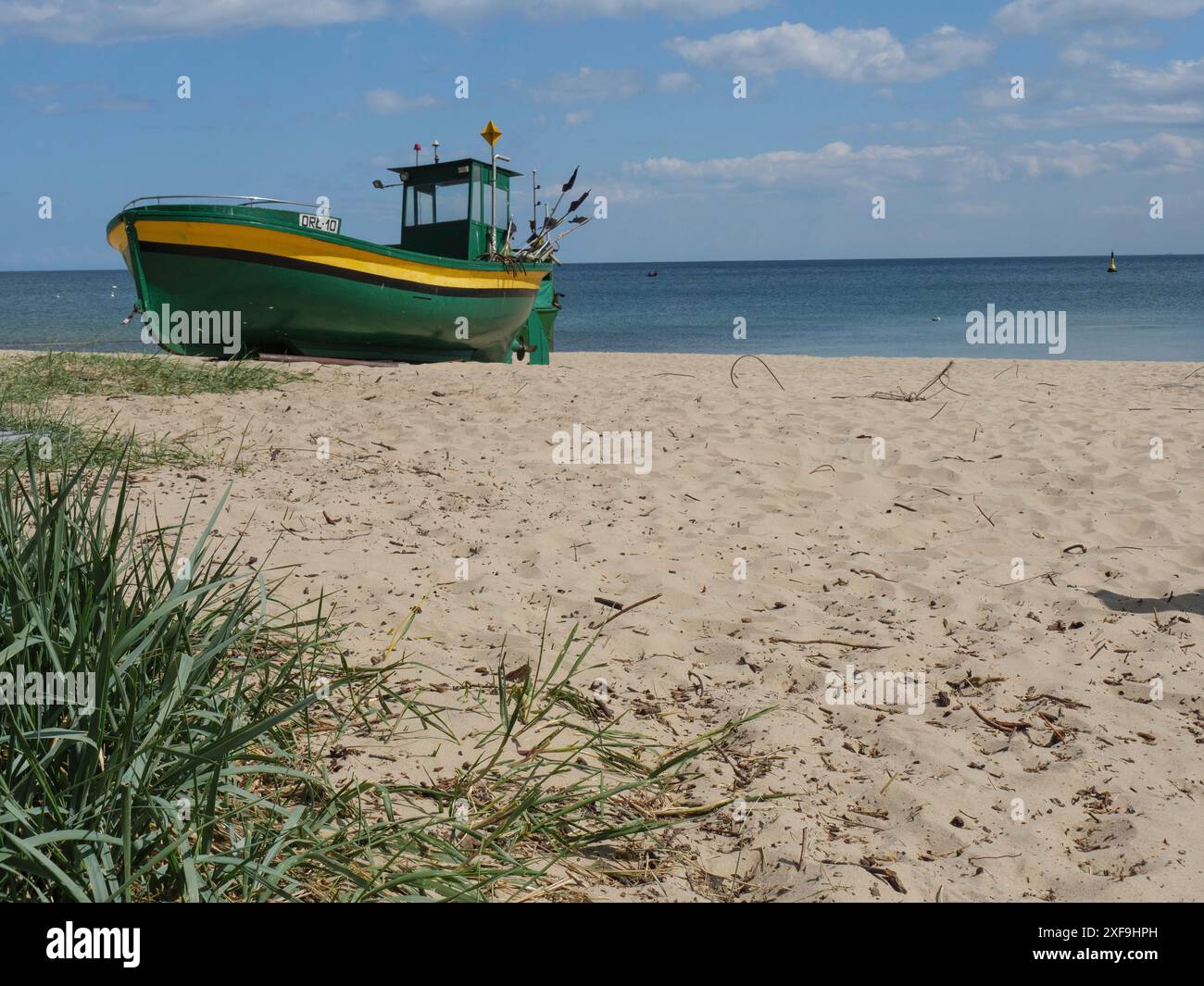 Una barca da pesca verde su una spiaggia sabbiosa con mare calmo e cielo blu sullo sfondo, sopot, Mar baltico, polonia Foto Stock