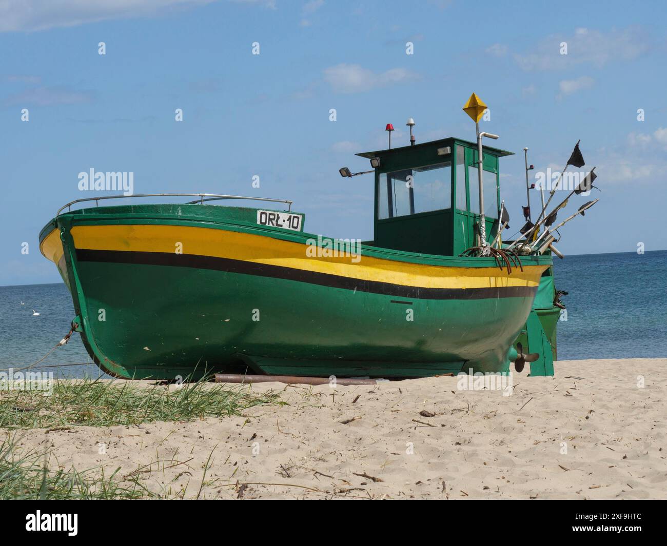 Barca da pesca verde su una spiaggia sabbiosa con vista sul mare calmo e il cielo blu sullo sfondo, sopot, Mar baltico, polonia Foto Stock