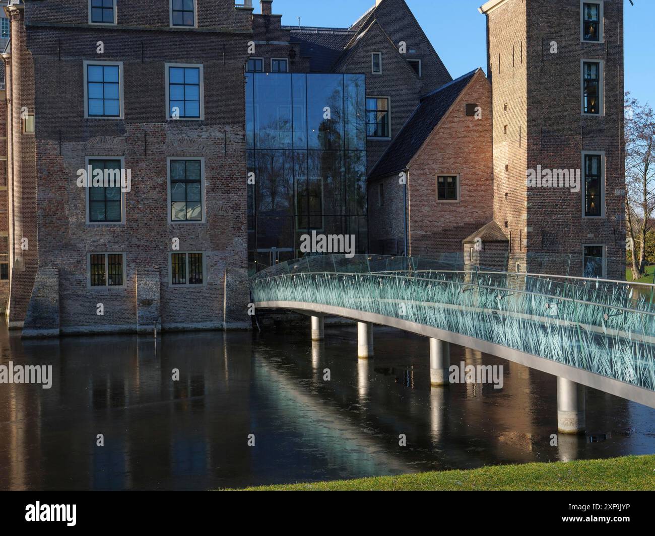 Primo piano di un castello con facciata in vetro, ponte moderno e edificio storico in mattoni, riflesso nell'acqua, a ruurlo, a gheldria, nei paesi bassi Foto Stock