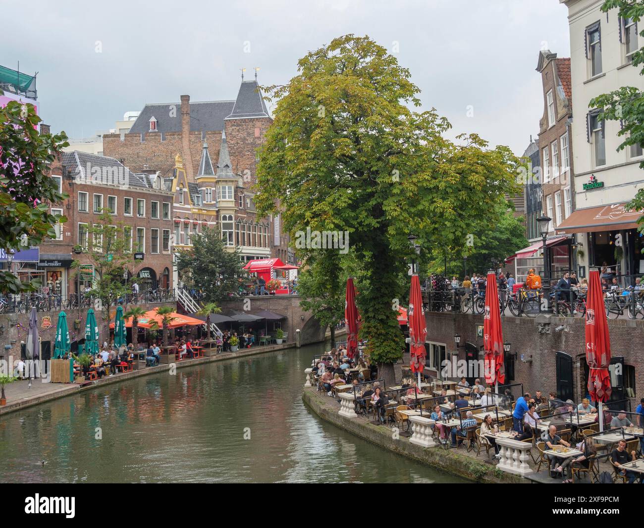 Vivace riva del canale con caffetterie all'aperto e ombrelloni colorati, atmosfera storica della città, utrecht, paesi bassi Foto Stock