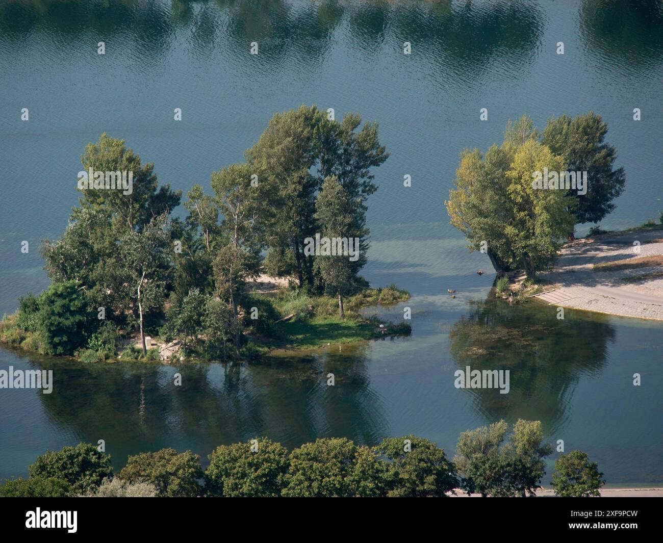 Tranquillo paesaggio fluviale con una piccola isola boscosa e riflessi sull'acqua, Vienna, Austria Foto Stock