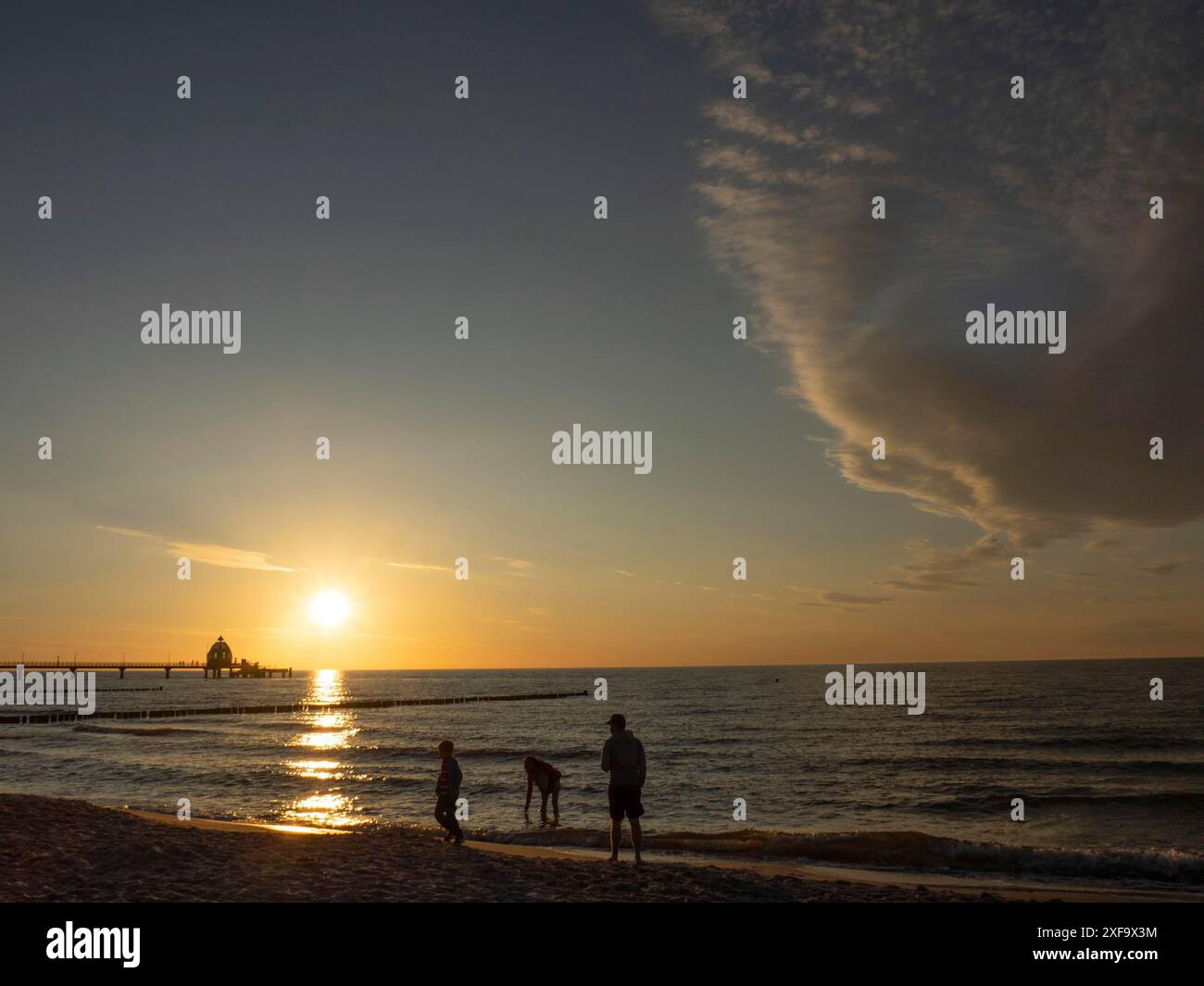 Una famiglia gode il tramonto sulla spiaggia sotto un affascinante cielo nuvoloso, ahrenshoop, zingst, Mar Baltico, Germania Foto Stock