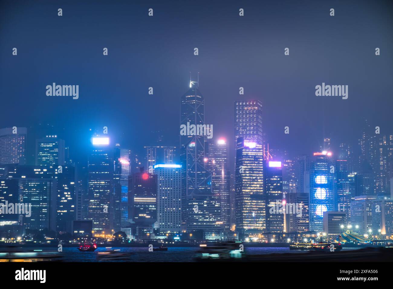 Splendida scena notturna con un colorato grattacielo luminoso e uno spettacolo di luci laser sul Victoria Harbour durante la nebbiosa giornata ad Hong Foto Stock