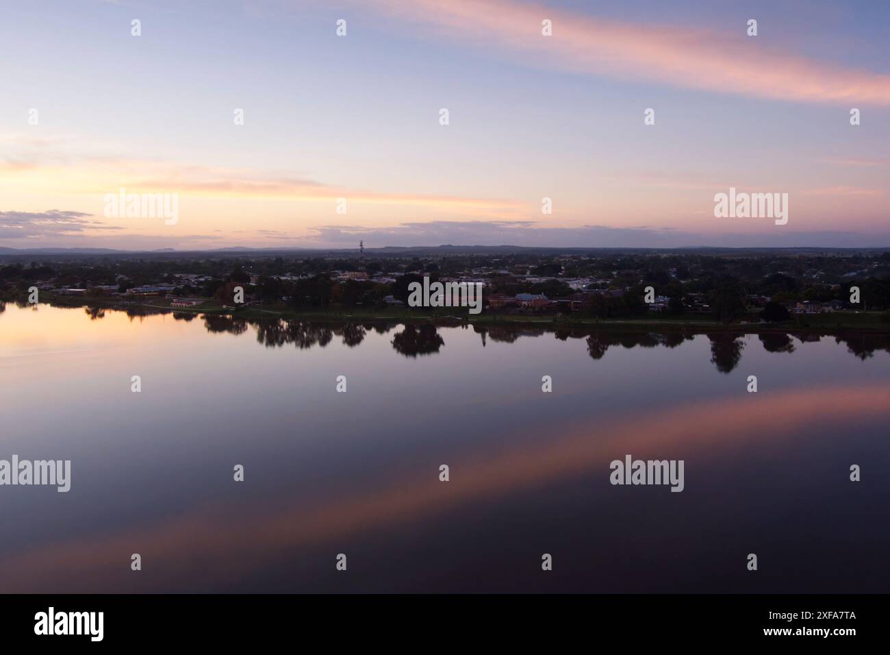 Una serena scena serale a Grafton, New South Wales, Australia. Il cielo è dipinto con sfumature di arancione e rosa mentre il sole tramonta sulla tranquilla Clare Foto Stock