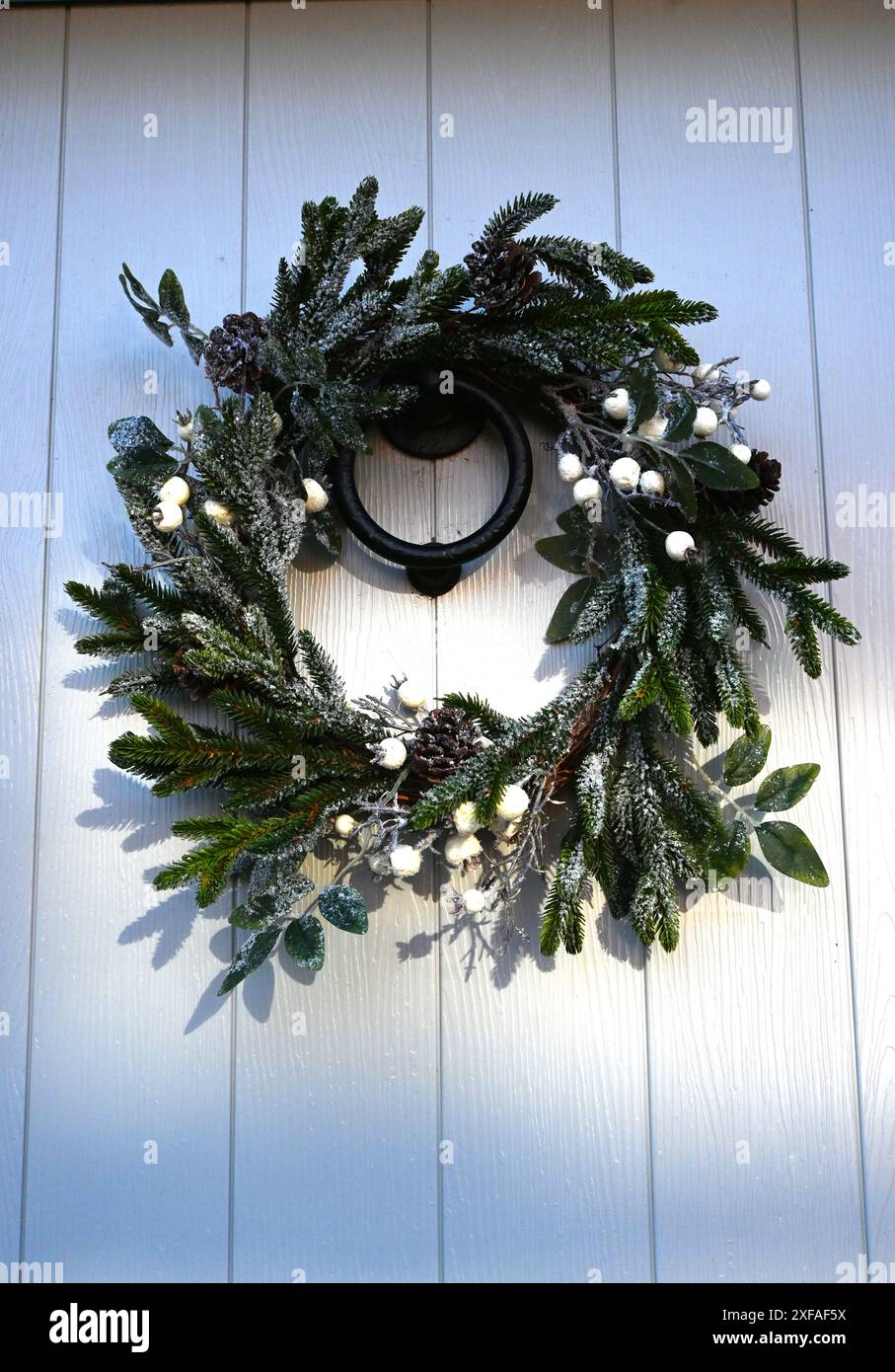 corona di natale sulla porta d'ingresso dipinta di bianco Foto Stock