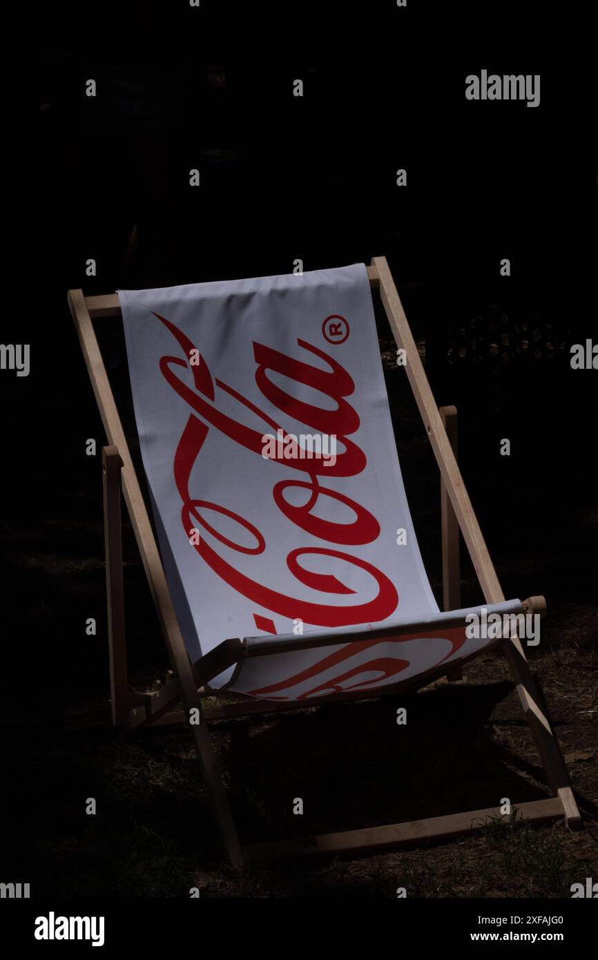 Materiale bianco con lettere rosse Coca Cola. Sedia, isolata su sfondo scuro, per esterni. Foto Stock