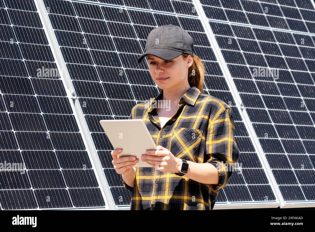 Un tecnico donna controlla il funzionamento dei pannelli solari utilizzando un tablet digitale. Foto Stock