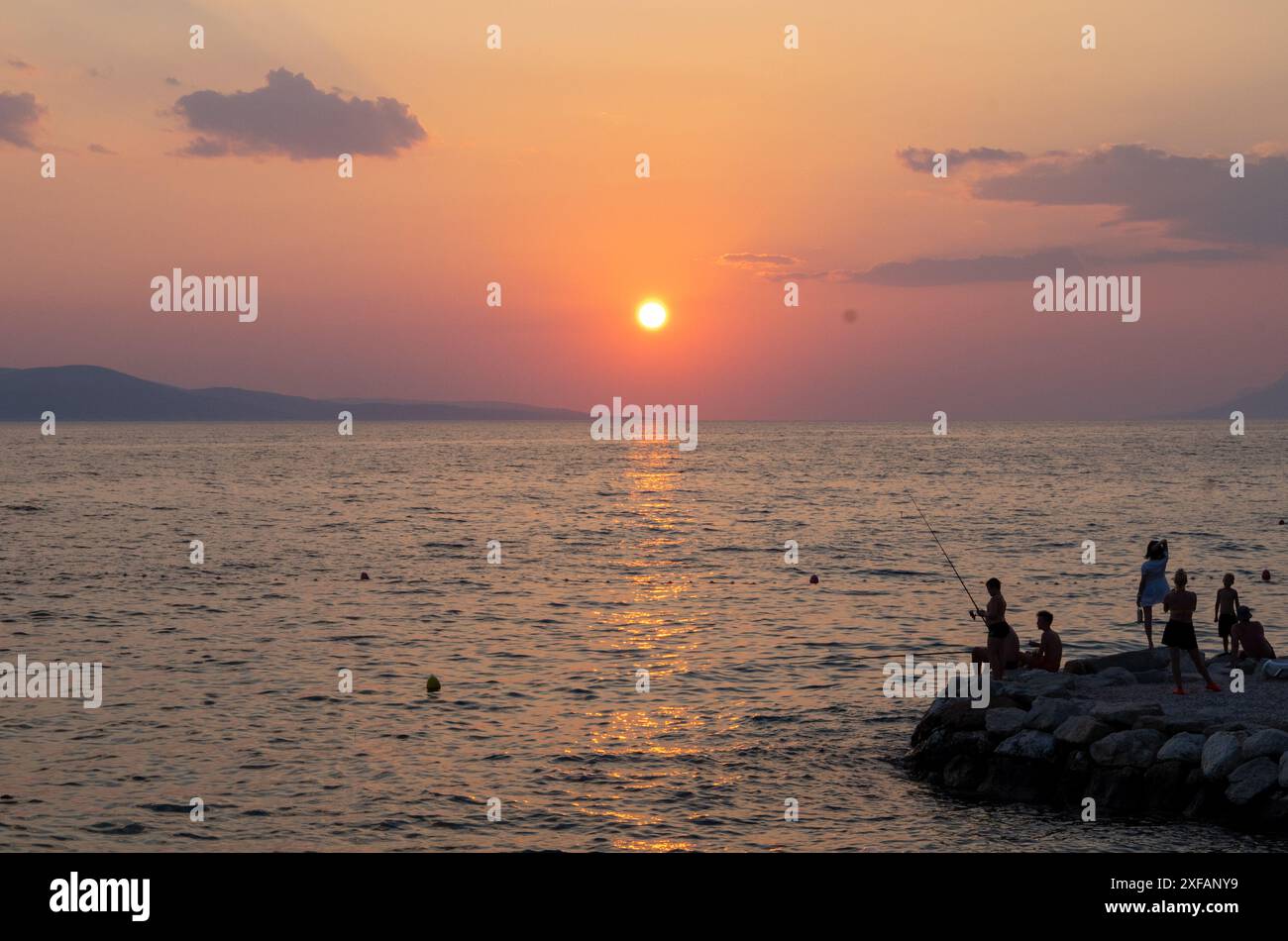 Makarska, Croazia. 1 ottobre 2023. Gli amanti della spiaggia si stagliano su una roccia al tramonto. Crediti: Viola Lopes/dpa/Alamy Live News Foto Stock