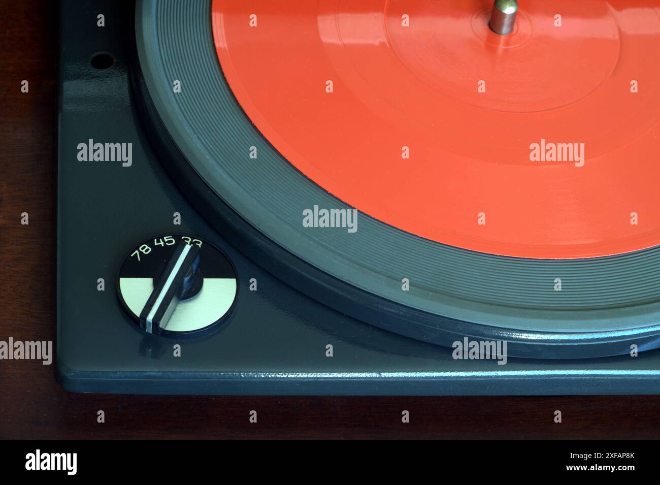 Parte di un lettore di dischi vintage in una custodia con finitura in legno con selettore di velocità e foto in vinile rosso flessibile da 7 pollici primo piano orizzontale Foto Stock