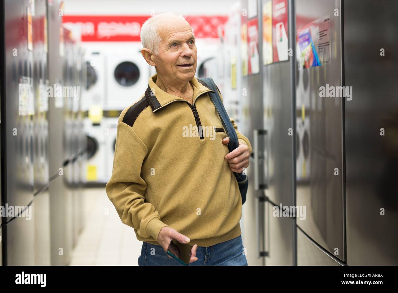 Pensionato Senor MAN che acquista un frigorifero nello showroom del negozio di elettrodomestici Foto Stock