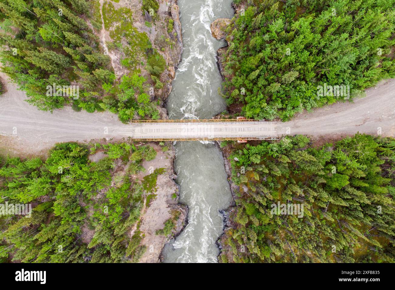 Colpo di droni di un fiume isolato e di un ponte situato nel nord del Canada, territorio dello Yukon durante l'estate. Vicino al fiume Ross. Foto Stock