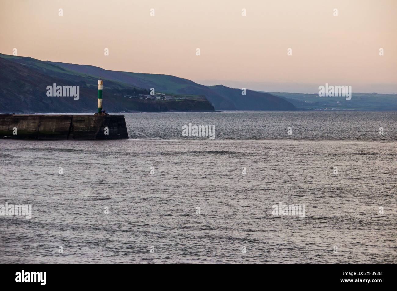 All'alba sulla costa gallese ad Aberystwyth, con la casa delle luci in primo piano. Foto Stock