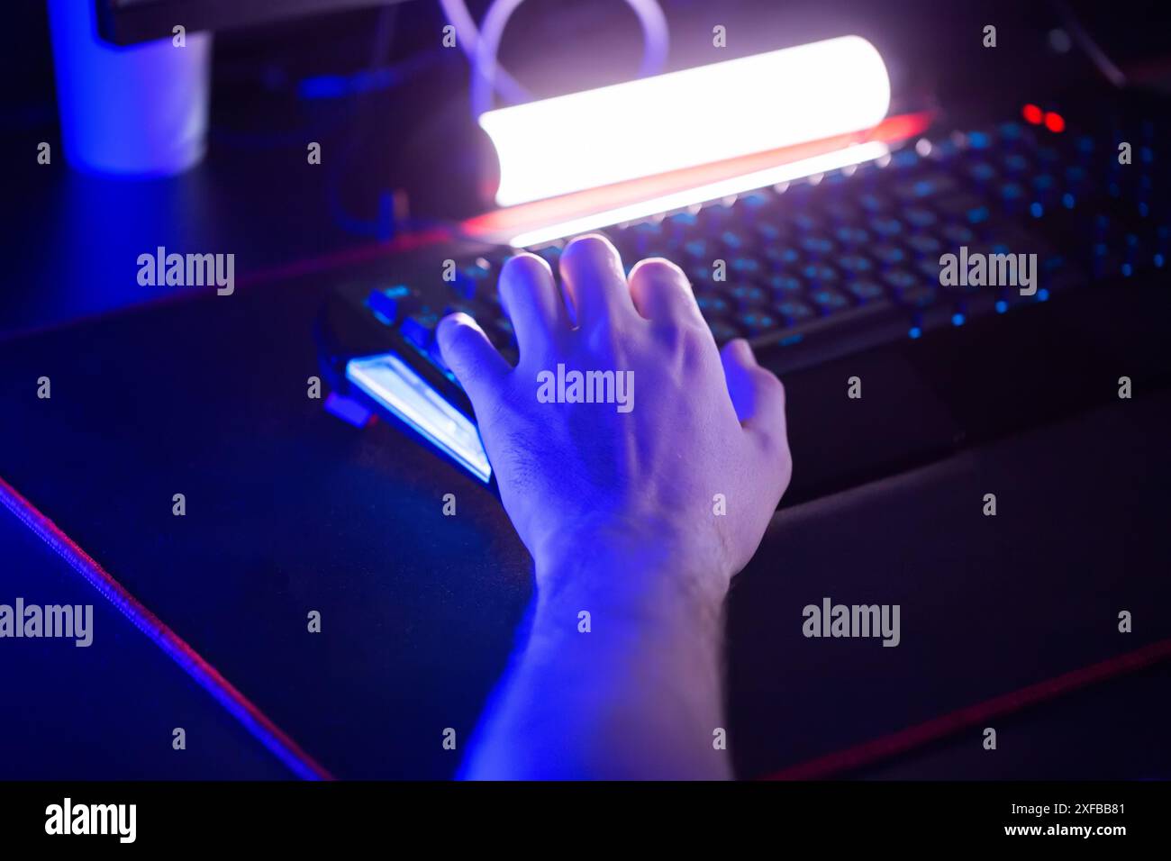 I giocatori giocano ai videogame su PC al club informatico. Clic con il dito sul pulsante della tastiera con fulmine RGB. Torneo di e-sport professionale Cyber sport Tea Foto Stock