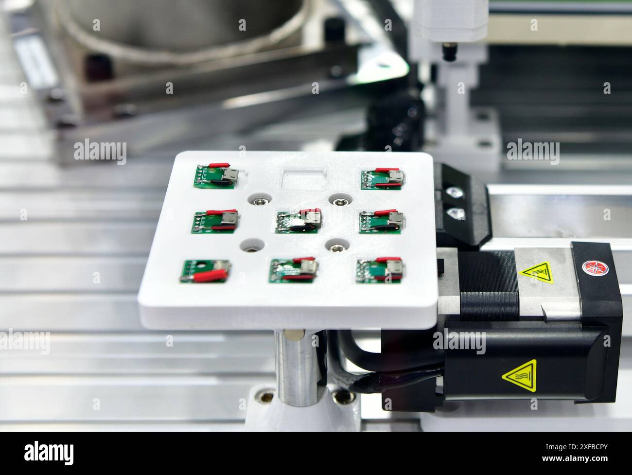 Macchinari di fabbrica al lavoro, Una piccola scheda a circuito stampato viene assemblata in un braccio robotico automatizzato Foto Stock