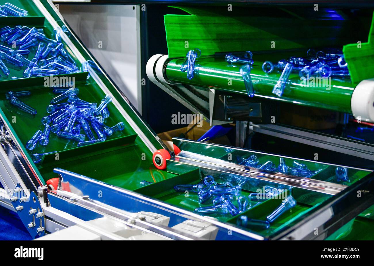Bottiglie di plastica blu nella linea di produzione in PET di produzione, prima che le bottiglie soffiino nella macchina di soffiaggio presso la fabbrica di acqua per bevande. Foto Stock
