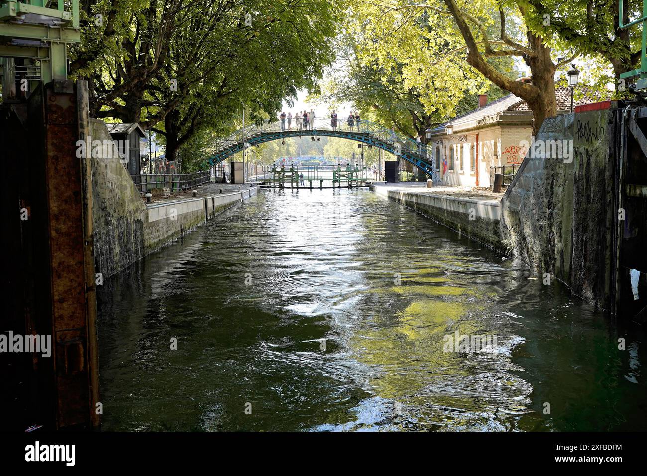 Canale con ponte sullo sfondo e alberi su entrambi i lati. Atmosfera estiva, Parigi, Francia Foto Stock