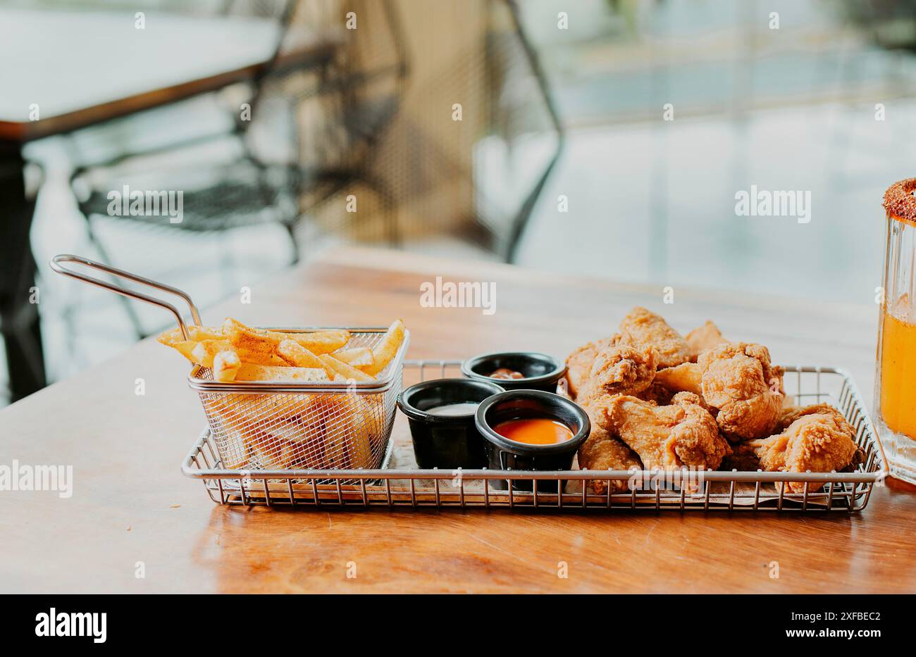 Deliziose ali piccanti con patatine fritte servite su un tavolo di legno con spazio per fotocopie. Ali di pollo speziate con patatine fritte servite sul tavolo con spazio per Foto Stock