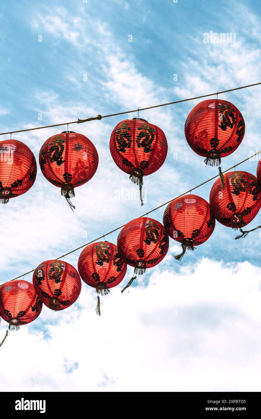 London Chinatown - Una serie di lanterne rosse appese nell'aria, contro un cielo blu brillante e soffici nuvole bianche Foto Stock