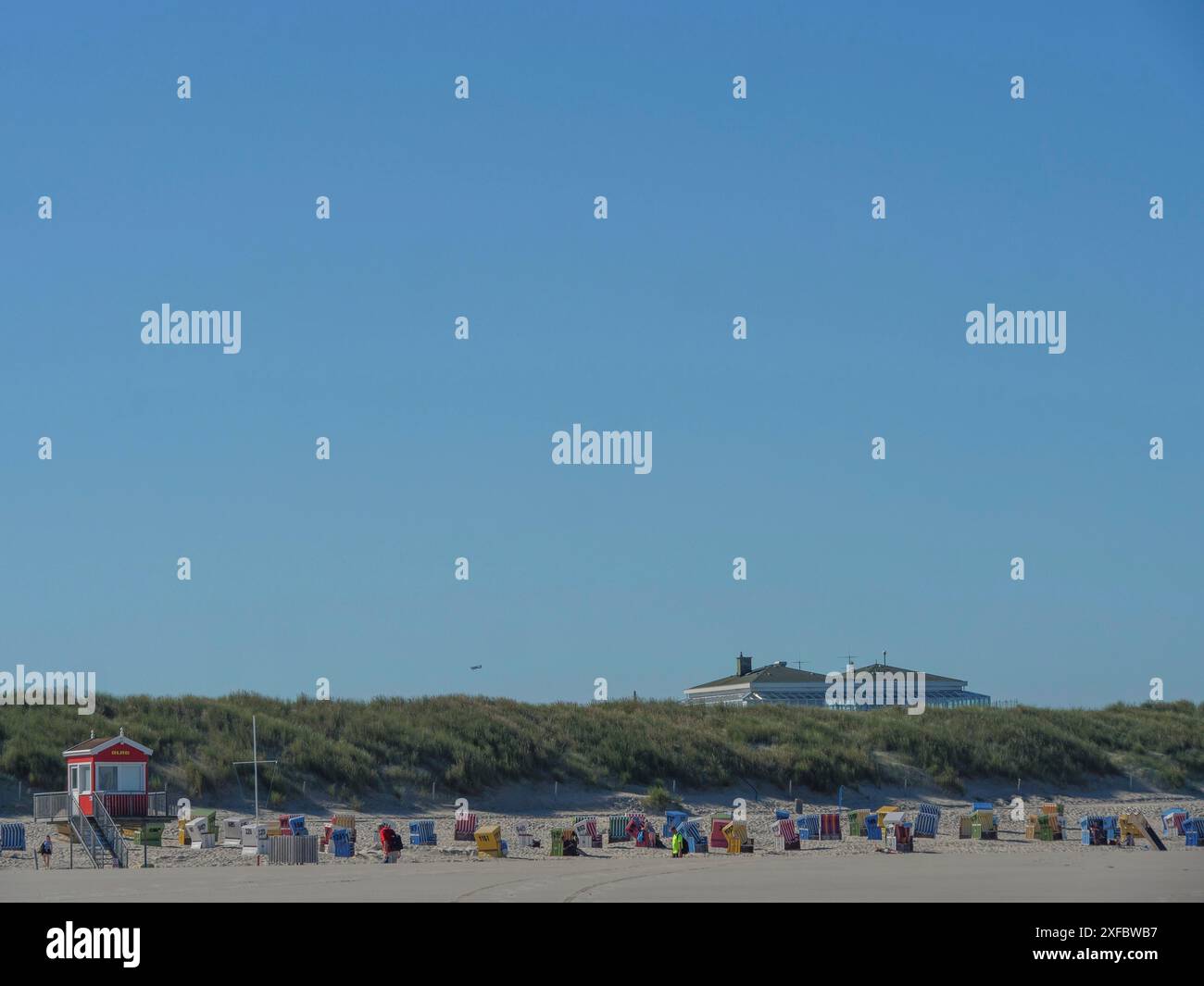 Vista di una fila di sdraio davanti alle dune erbose sotto un cielo azzurro Foto Stock