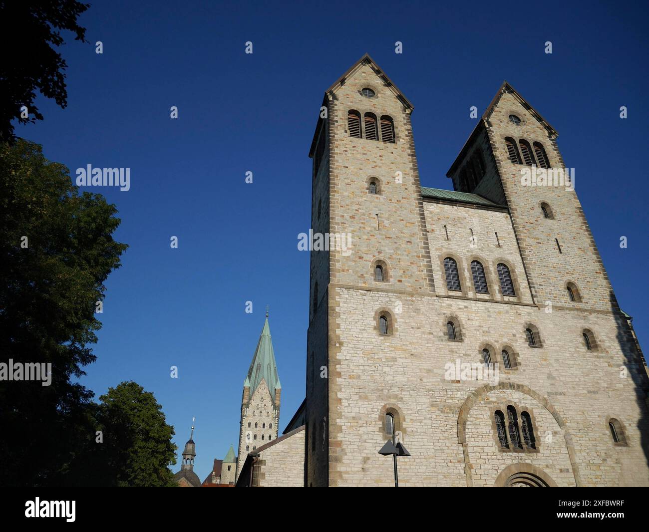Chiesa con due caratteristiche torri in mattoni contro un cielo blu, parzialmente oscurata dagli alberi, paderborn, Renania settentrionale-Vestfalia, germania Foto Stock Chiesa con due caratteristiche torri in mattoni contro un cielo blu, parzialmente oscurata dagli alberi, paderborn, Renania settentrionale-Vestfalia, germania Foto Stock