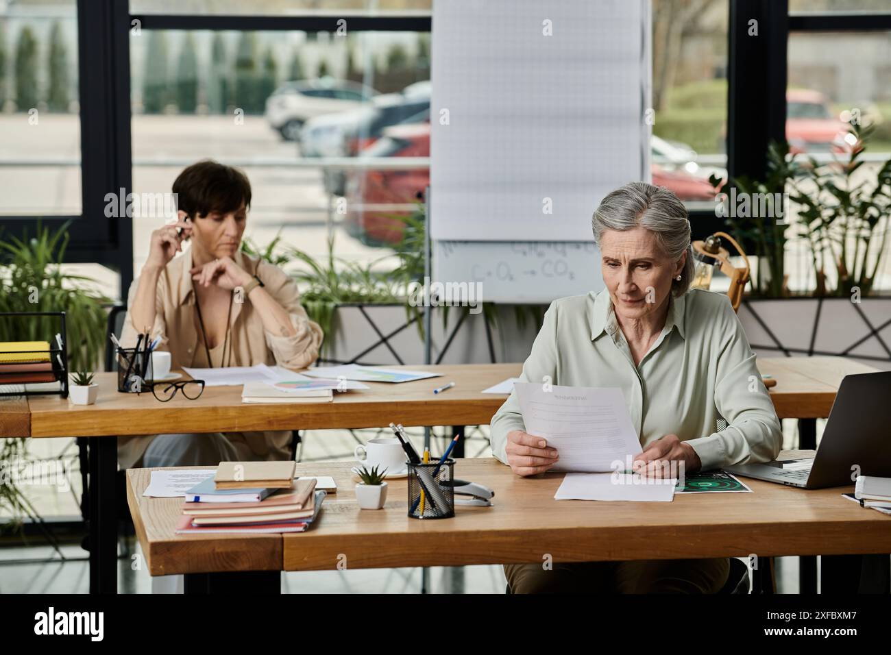 Due donne si sono concentrate sul lavoro a un tavolo. Foto Stock