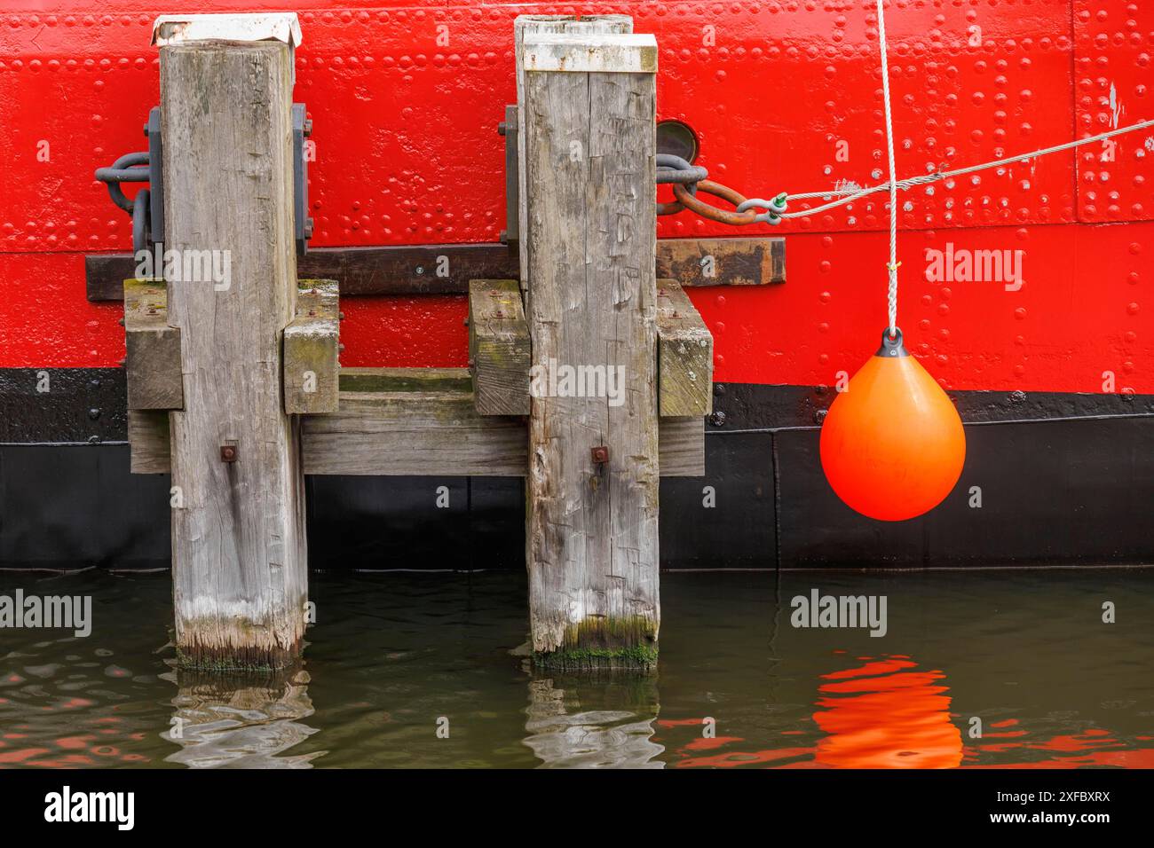 Primo piano di una nave con scafo rosso e passerelle in legno nell'acqua, bremerhaven, germania Foto Stock