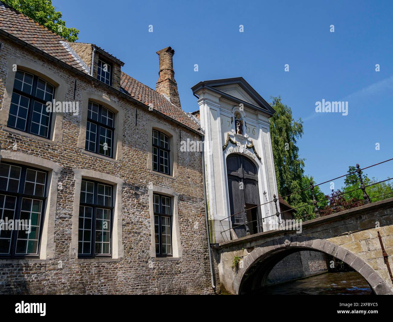 Ponte di pietra su un piccolo fiume di fronte agli edifici storici, Bruges, Fiandre, Belgio Foto Stock