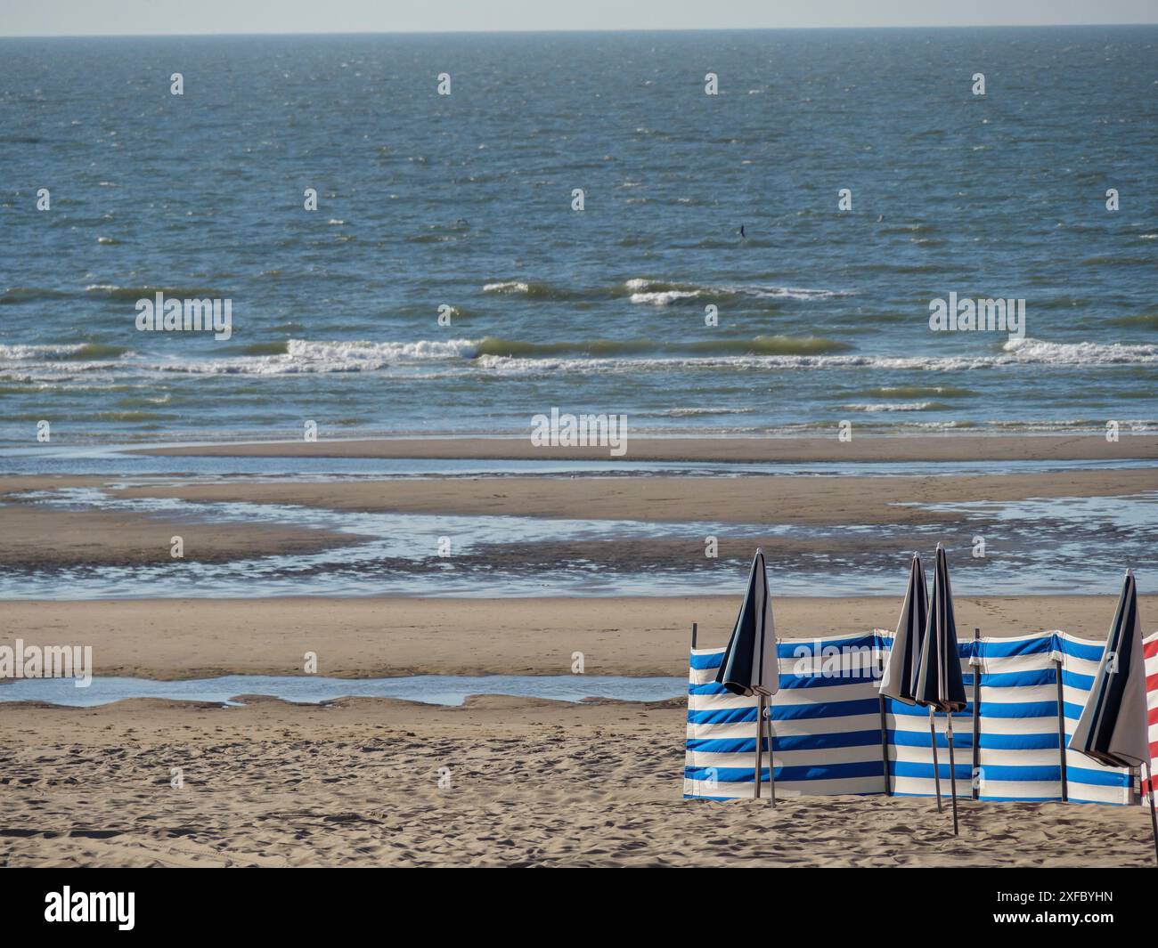 Vista sulla spiaggia con nastro blu e bianco vicino al mare, onde calme, De Haan, Fiandre, Belgio Foto Stock