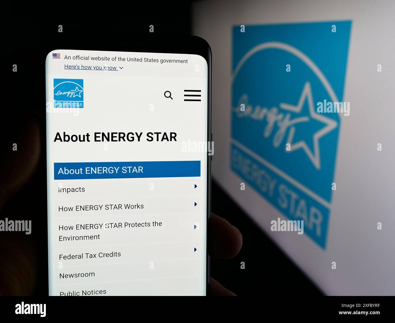 Persona che tiene un cellulare con la pagina Web del programma di efficienza energetica degli Stati Uniti Energy Star davanti al logo. Messa a fuoco al centro del display del telefono. Foto Stock