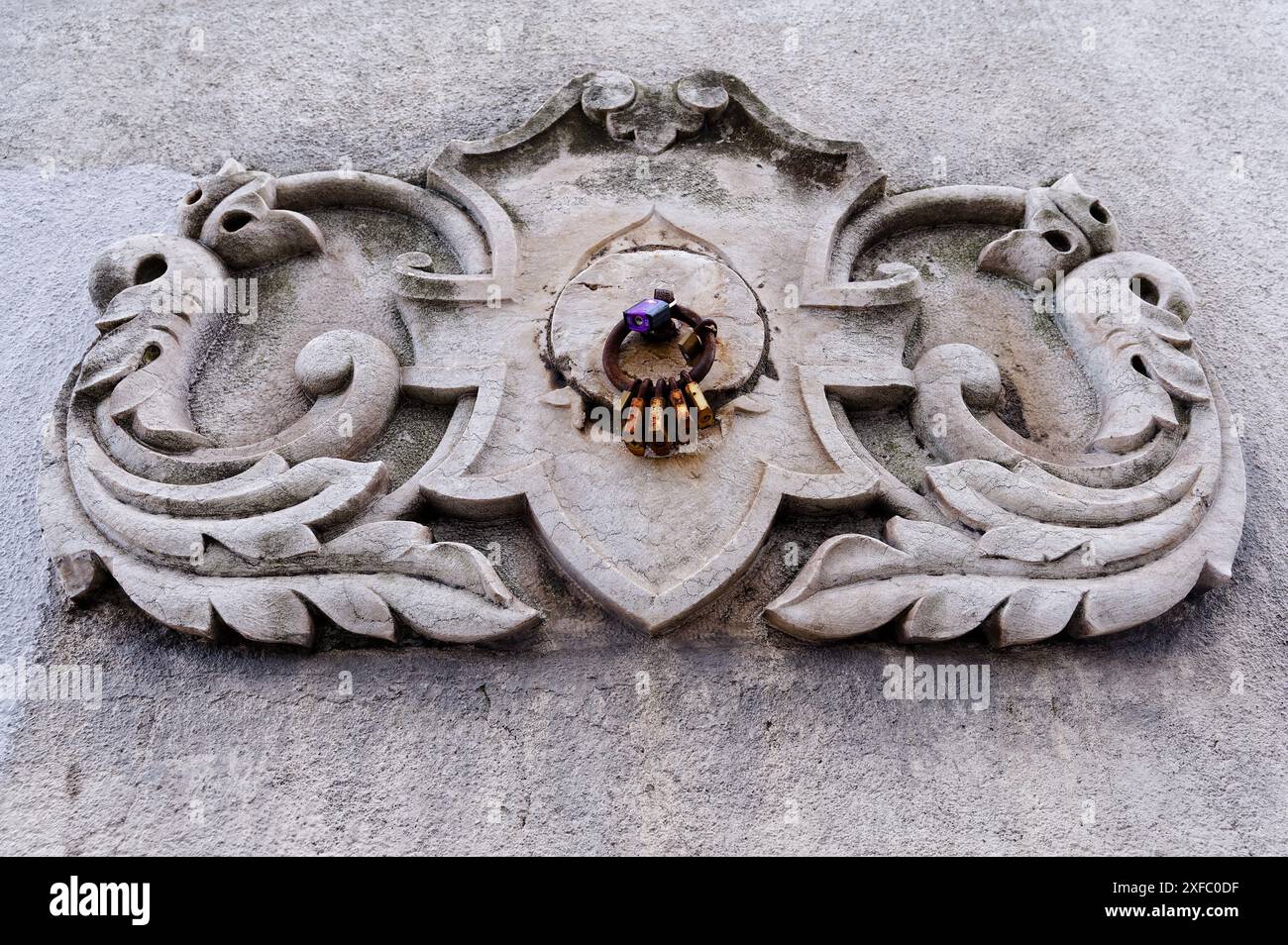 Un intaglio ornamentale in pietra caratterizzato da un motivo naturale stilizzato e un anello centrale adornato da lucchetti Foto Stock