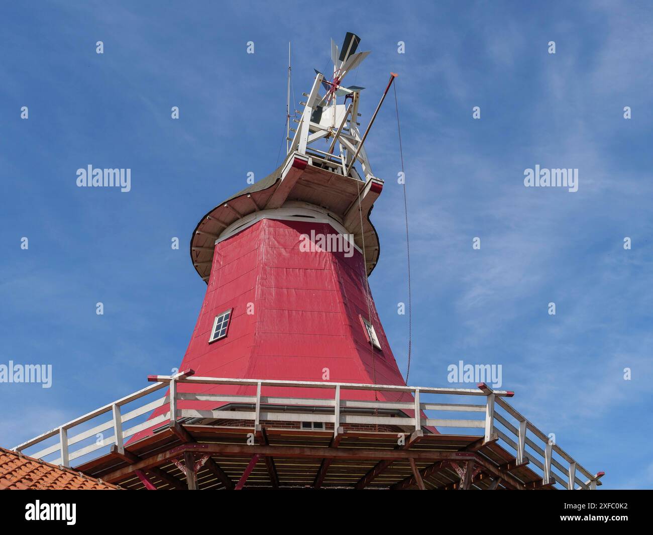 Un mulino a vento rosso con costruzione in legno e grandi ruote a pale sotto un cielo blu, Greetsiel, Frisia orientale, Germania Foto Stock