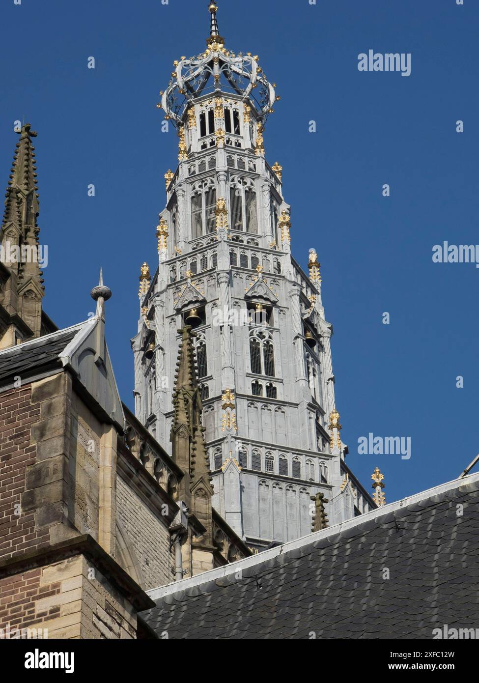 Alta torre della chiesa riccamente decorata con accenti dorati, su un cielo blu e dettagli gotici Foto Stock