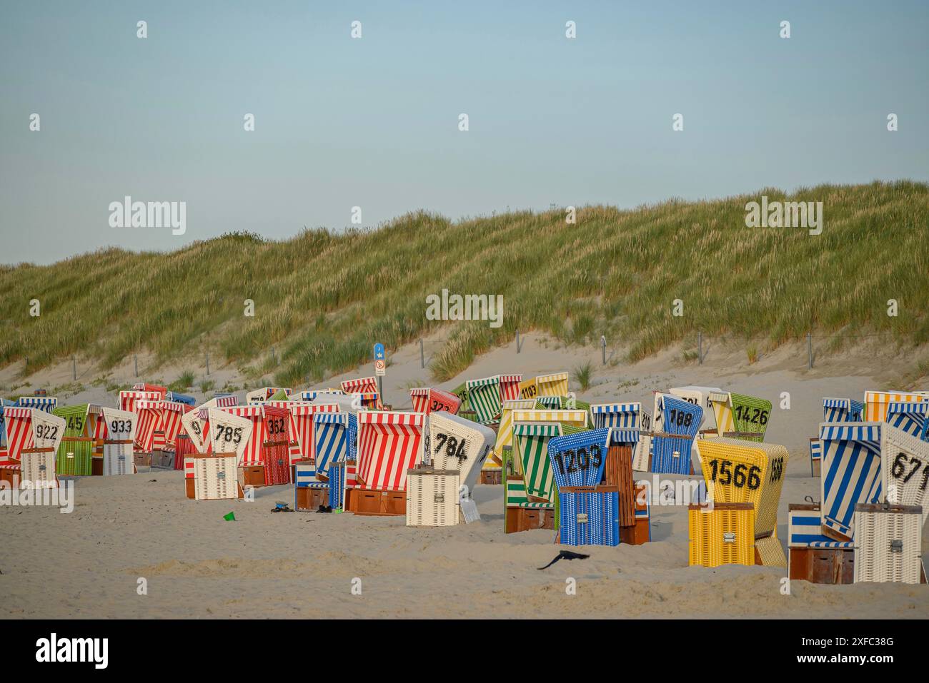 Colorate sedie a sdraio si trovano in fila sulla spiaggia sabbiosa dietro le dune, langeoog, frisia orientale, germania Foto Stock