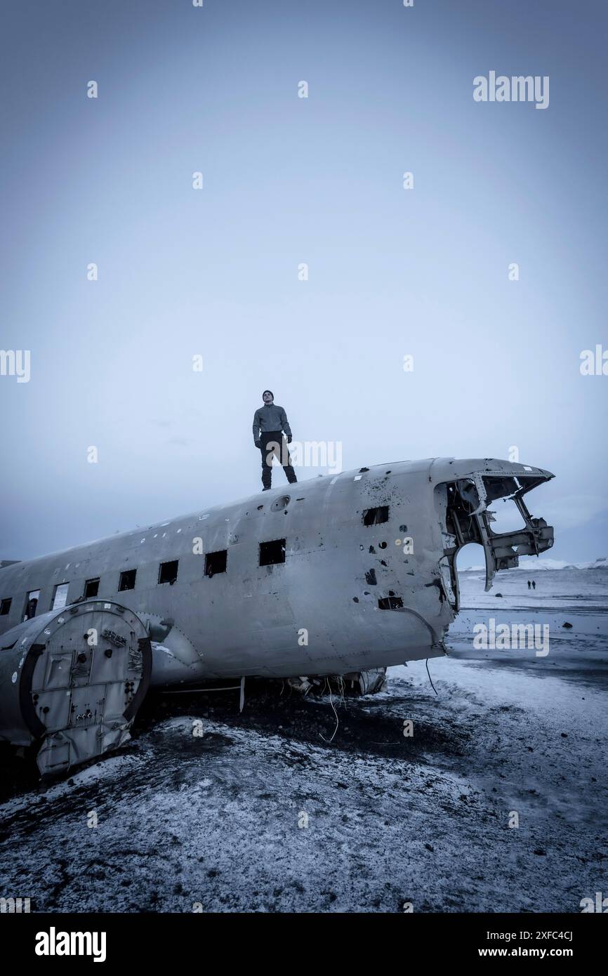 Un uomo sull'aereo militare schiantato a Solheimasandur in inverno con il terreno ghiacciato Foto Stock