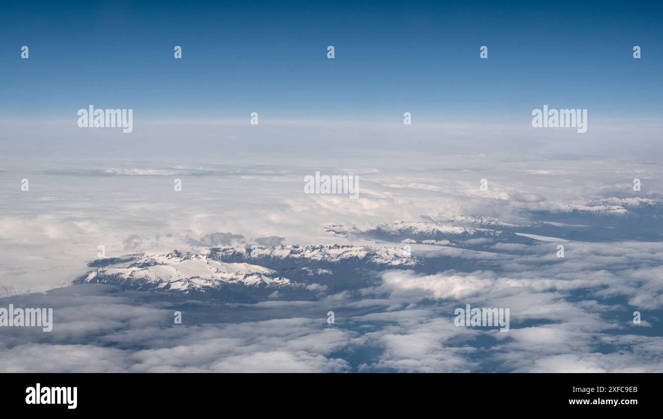 Vista panoramica sui fiordi orientali dell'Islanda dalla finestra dell'aeroplano. Volare sopra le nuvole. Vista dalla finestra dell'aereo. Foto Stock